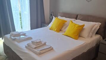 Una cama bien hecha con toallas, una lámpara de noche y decoración en la pared.