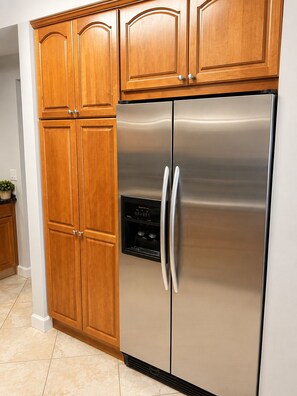 A stainless steel refrigerator with a water dispenser, wooden cabinets, and a tiled floor. - Waterfront Condo in Heart of Islamorada, Boat slip (Islamorada)