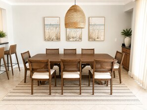 A dining room with a large wooden table, six chairs, a woven pendant light, and three framed artworks on the wall. - Waterfront Condo in Heart of Islamorada, Boat slip (Islamorada)