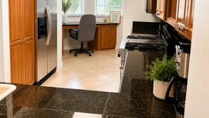 Una cocina con armarios de madera, un refrigerador de acero inoxidable, una estufa y una ventana con vistas a la vegetación.