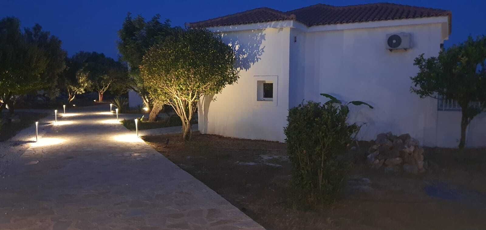 Un edificio blanco con techo de tejas, una ventana pequeña y un equipo de aire acondicionado.