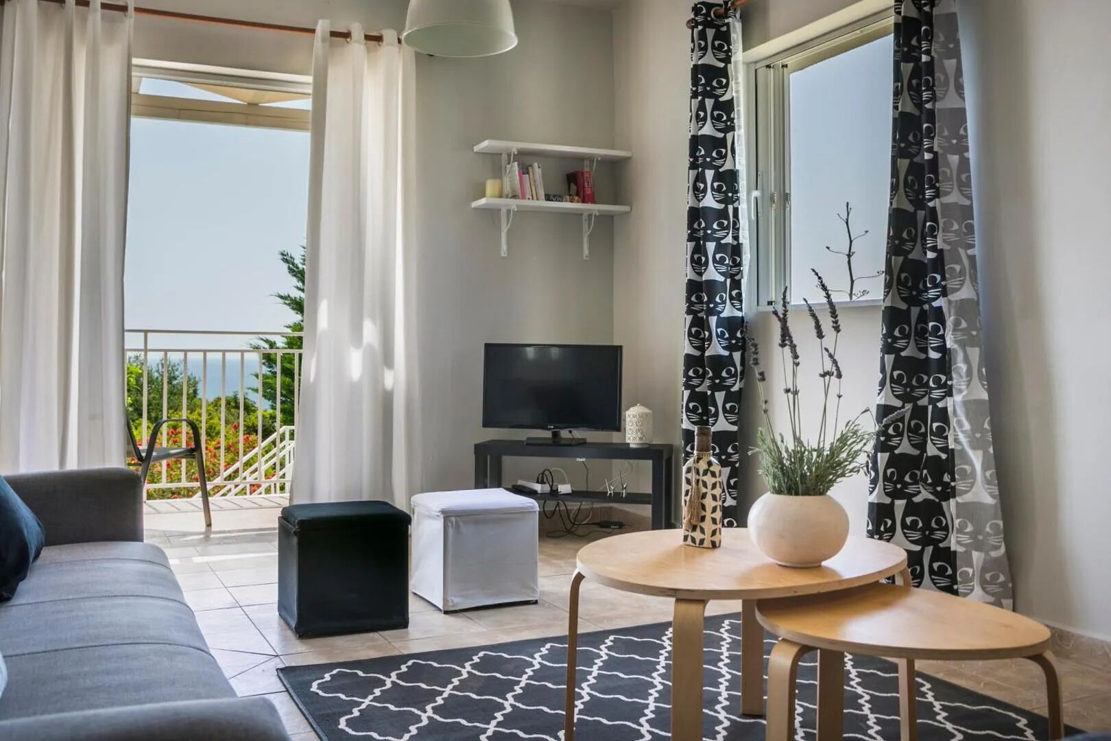 Un salon avec un canapé, un téléviseur, une petite table et un balcon doté d’une balustrade.