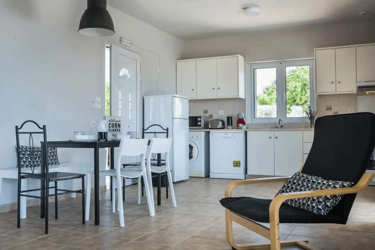 Una cocina compacta con comedor, lavadora y una silla con cojín estampado.