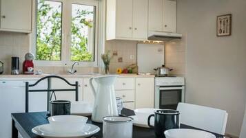 A kitchen with white cabinets, a stove, and a window with greenery outside.