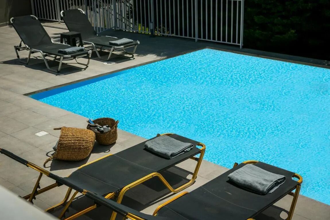 A swimming pool with lounge chairs and a small table.