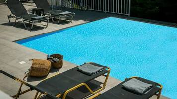 A swimming pool with lounge chairs and a small table.