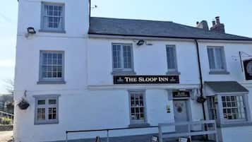 A white building with a sign reading 'The Sloop Inn' and a bar entrance.