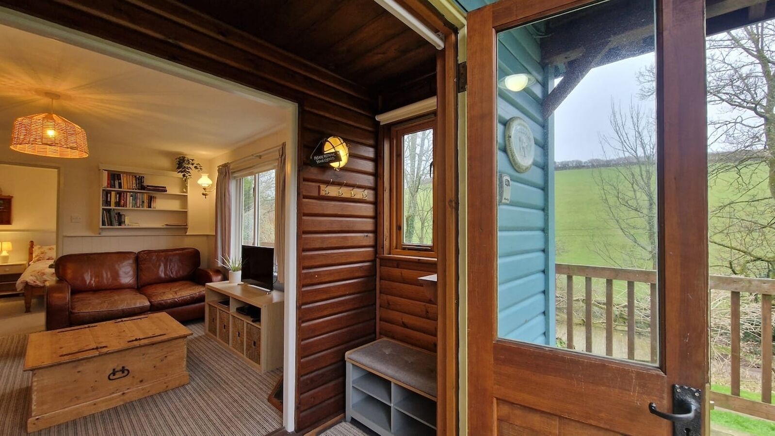 A cozy cabin interior with a wooden interior, a sofa, a television, and a view of the outdoors.