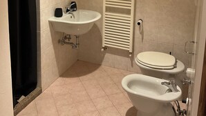 Ein Badezimmer mit Waschbecken, Spiegel, Handtuchhalter, Toilette und Bidet.