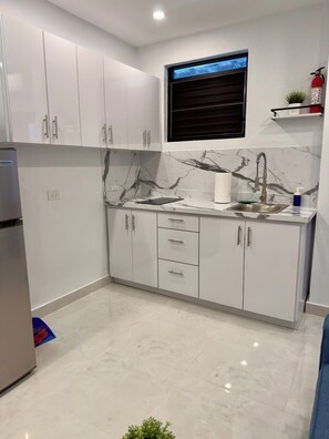 A modern kitchen with white cabinets, a marble countertop, a built-in sink, and a window above the sink. - Colonial Apartment w/ Fast Wi-Fi & Parking, Near (San Juan)