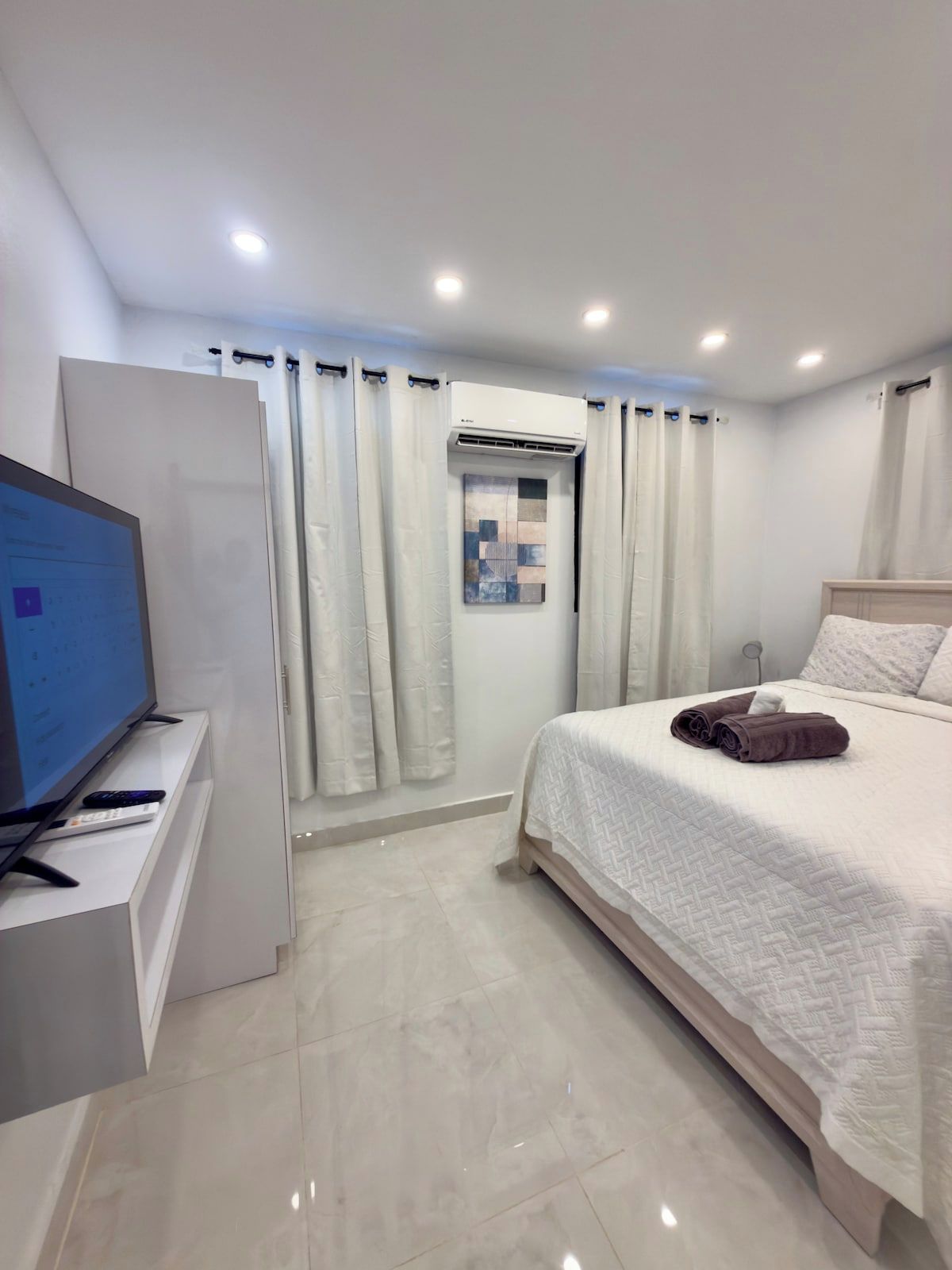 Une chambre d’hôtel équipée d’un lit, d’un téléviseur posé sur un meuble et d’un appareil de climatisation.