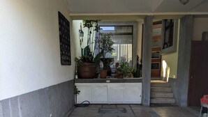 En fliseterrasse med plantekasser, vandslange og trappe op til et højere niveau.