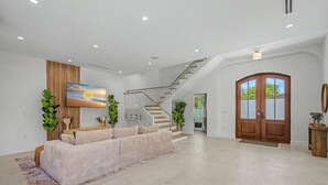 Ein geräumiger Wohnbereich mit einer Couch, einer Treppe und einer großen Holztür.