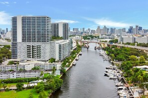 Ein modernes, hoch aufragendes Hotel mit markanter Fassade, eine Marina mit Booten und eine Stadtansicht im Hintergrund.