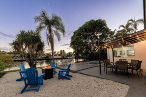 A patio with outdoor seating, a fire pit, and a pool area. - Casa Sunset Waterfront Stay (Wilton Manors)