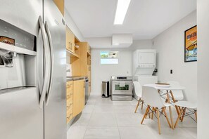 Une cuisine moderne dotée d’appareils électroménagers en acier inoxydable, de meubles en bois et d’un coin repas avec des chaises blanches.