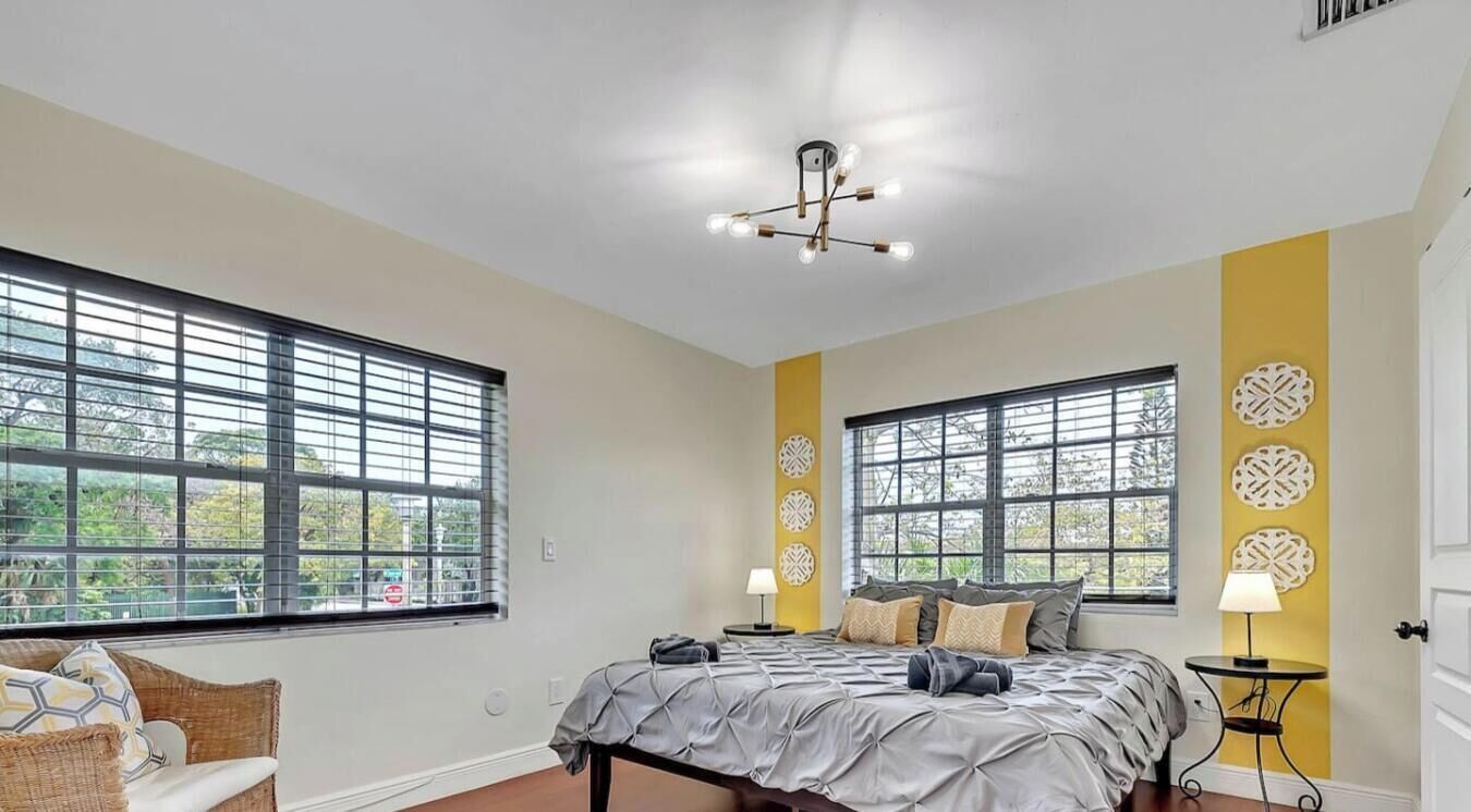 Una camera da letto con un letto, due comodini, una finestra e una lampada a soffitto.