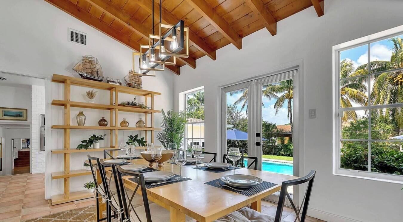 A dining area with a wooden table, chairs, and a hanging light fixture.