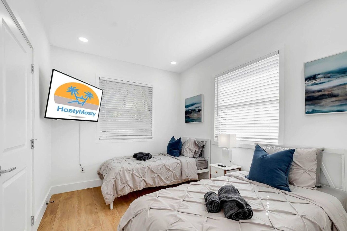 A bedroom with two beds, a TV, and artwork on the walls.