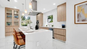 A modern kitchen with a central island, wooden cabinets, and pendant lighting. - Gated Miami Luxury Oasis Pool & BBQ I 4-Bed, 4-Bath (Miami)