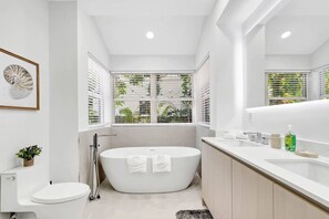 A modern bathroom with a freestanding bathtub, a toilet, and a sink with a mirror. - Gated Miami Luxury Oasis Pool & BBQ I 4-Bed, 4-Bath (Miami)