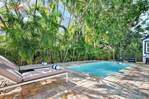 A pool with lounge chairs and dense tropical foliage. - Gated Miami Luxury Oasis Pool & BBQ I 4-Bed, 4-Bath (Miami)
