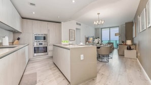 Una cocina moderna con electrodomésticos integrados, una isla central y un comedor con vistas.