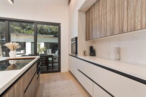 A modern kitchen with a large window, wooden cabinets, and a marble backsplash. - Luxury Miami Oasis Heated Pool & BBQ with Guesthouse (Miami)