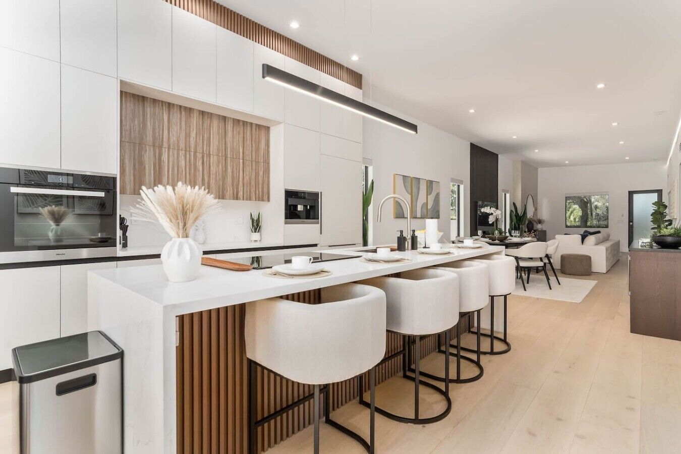A modern kitchen with a central island, built-in appliances, and a dining area with a sofa and chairs.
