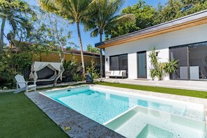 Ein modernes Haus mit Swimmingpool, einer überdachten Lounge und einem gepflegten Garten.