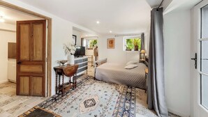Une chambre à coucher avec un lit, un bureau avec une télévision, une armoire et une grande fenêtre.