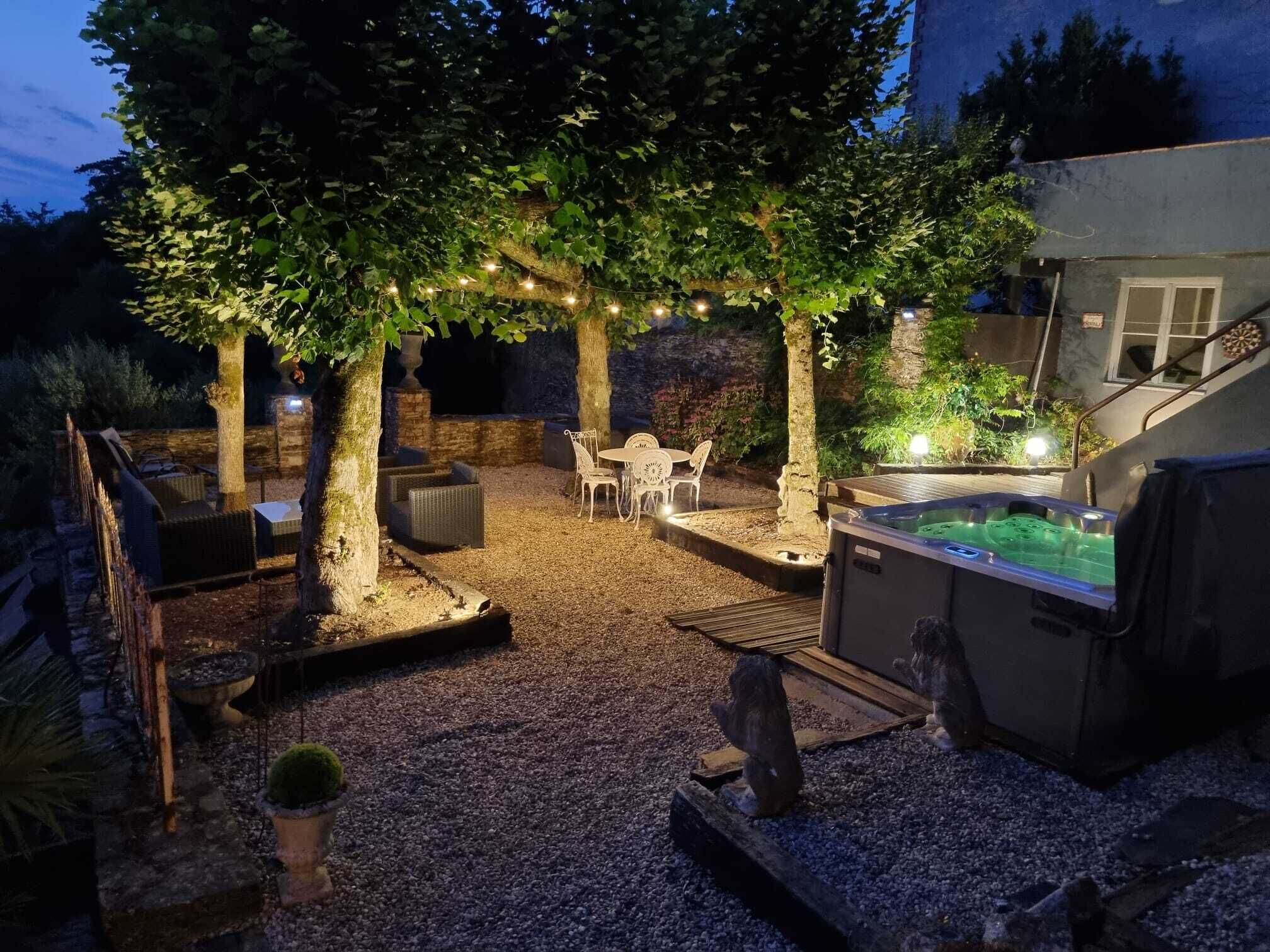 A patio area with a hot tub, seating, and string lights.