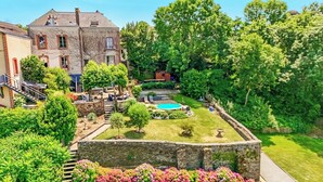 Une cour avec une piscine, des murs en pierre et une végétation luxuriante.