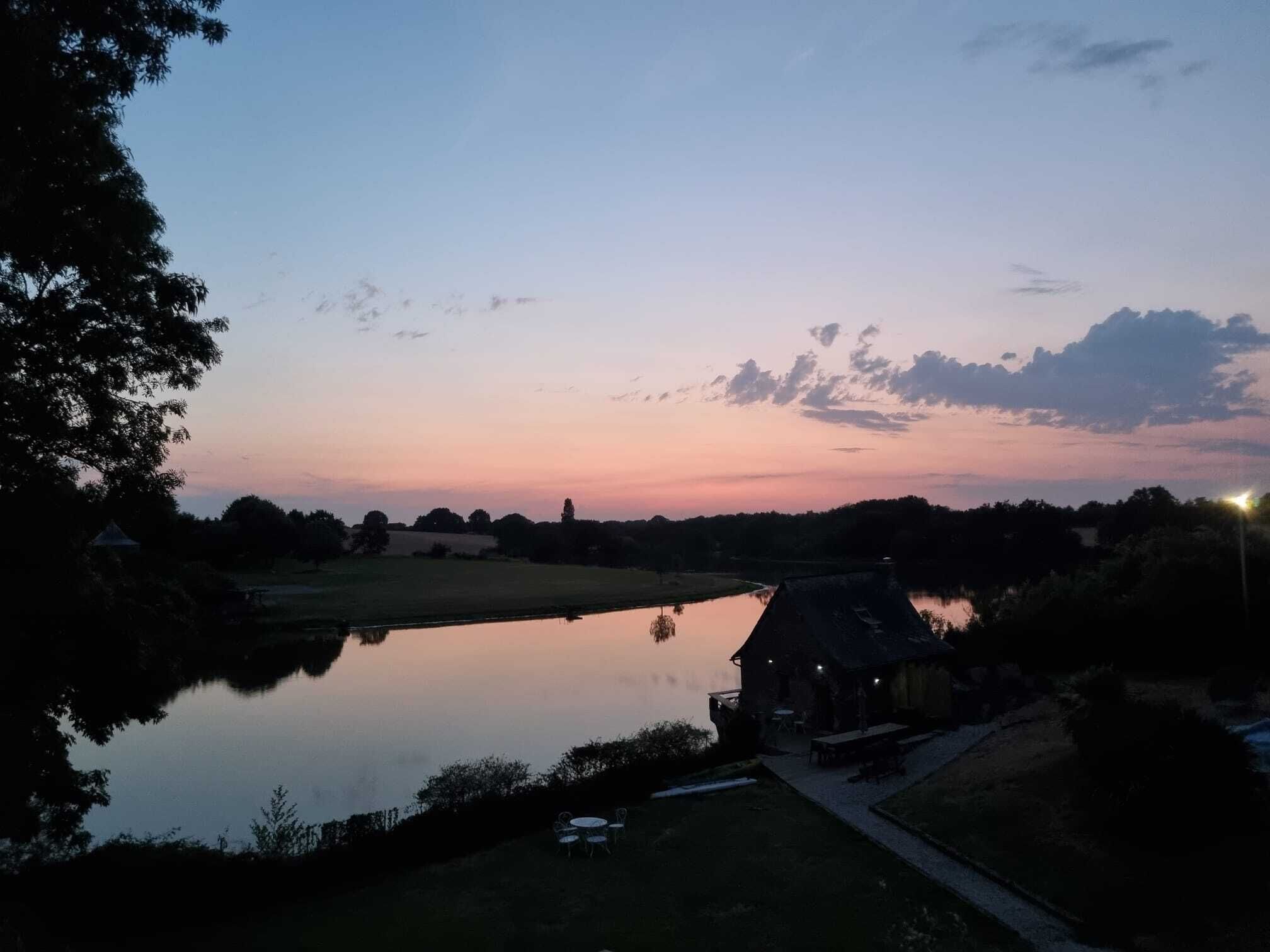 Blick auf einen See mit einem Gebäude, Außenbereich und blauem Himmel.