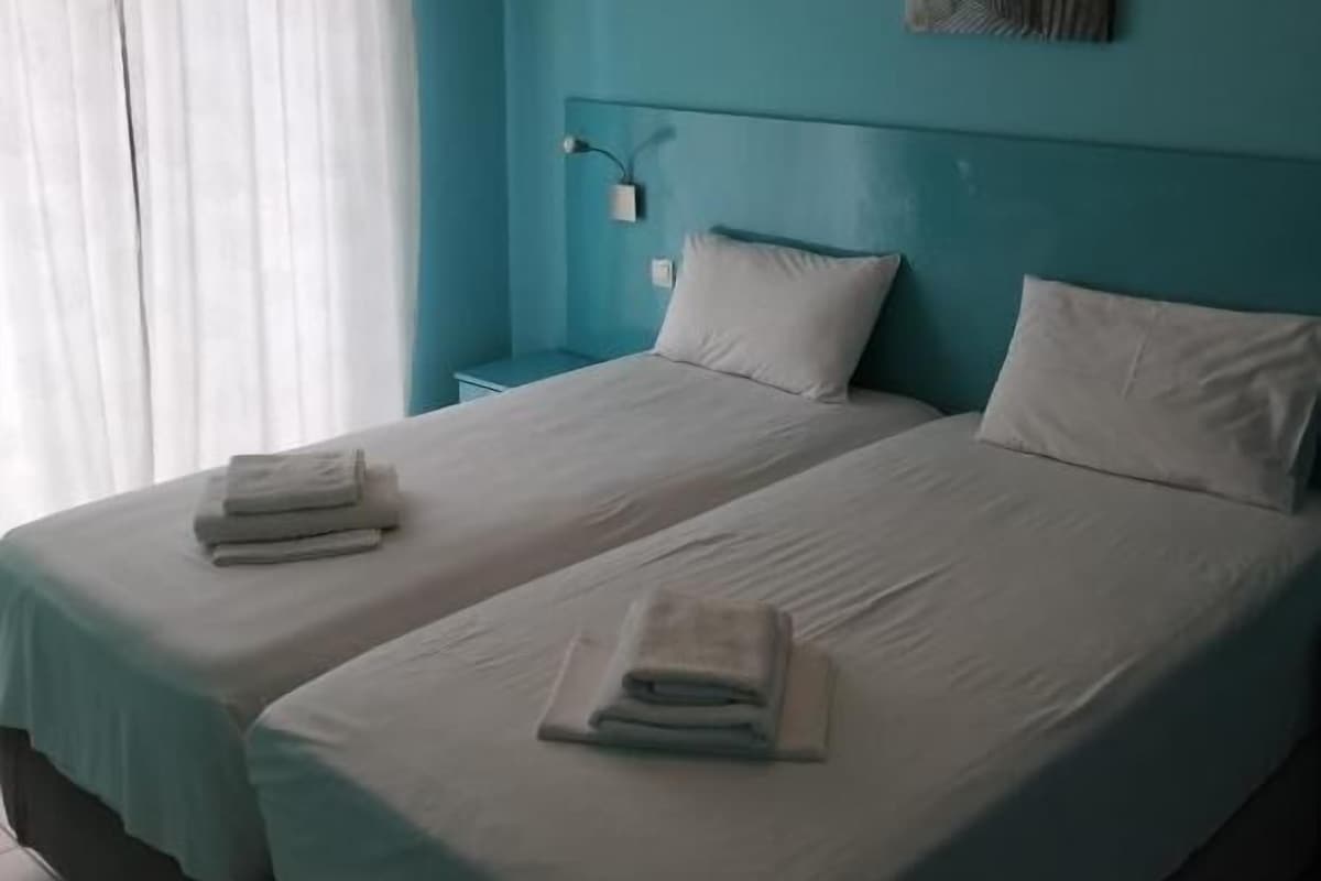 A room with two beds, a nightstand, a lamp, and a painting on the wall.