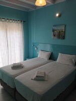 Una habitación con dos camas, una mesita de noche, una lámpara y un cuadro en la pared.
