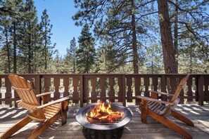 Una terraza con dos sillas Adirondack y un brasero.
