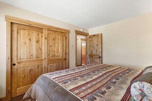 Ein Schlafzimmer mit einem großen Bett, einem Holzschrank und einer Tür zu einem anderen Raum.
