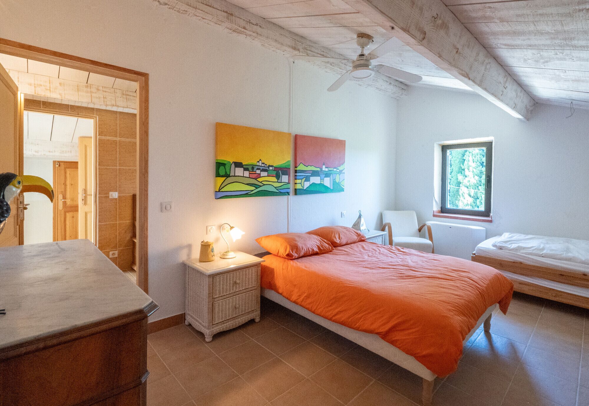 A bedroom with a bed, nightstand, dresser, and a ceiling fan.