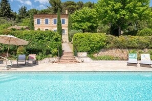 A pool area with lounge chairs, a staircase leading to a building, and lush greenery. - Marie-Marthe | Luxury bastide with private pool in Aups, Provence (Aups)