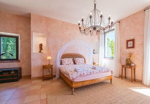 A bedroom with a bed, a chandelier, a window, and a wall-mounted TV. - Marie-Marthe | Luxury bastide with private pool in Aups, Provence (Aups)