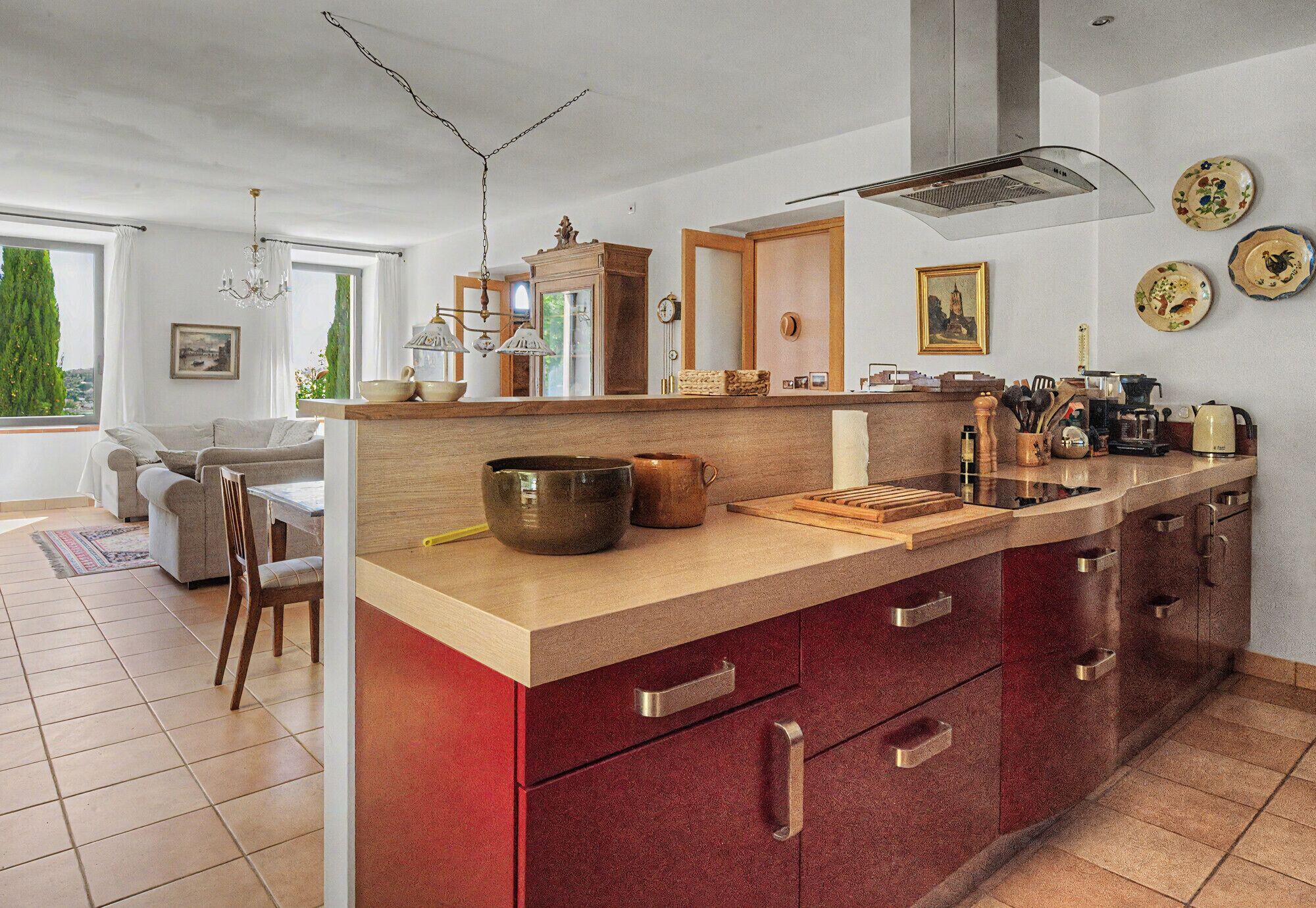 A modern kitchen with a large island, wooden cabinets, and a dining area with a sofa and table.