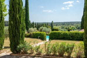 A landscaped garden with tall cypress trees, a swimming pool, and a view of the countryside. - Marie-Marthe | Luxury bastide with private pool in Aups, Provence (Aups)