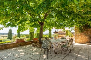 An outdoor patio with a table and chairs, surrounded by greenery and a stone wall. - Marie-Marthe | Luxury bastide with private pool in Aups, Provence (Aups)