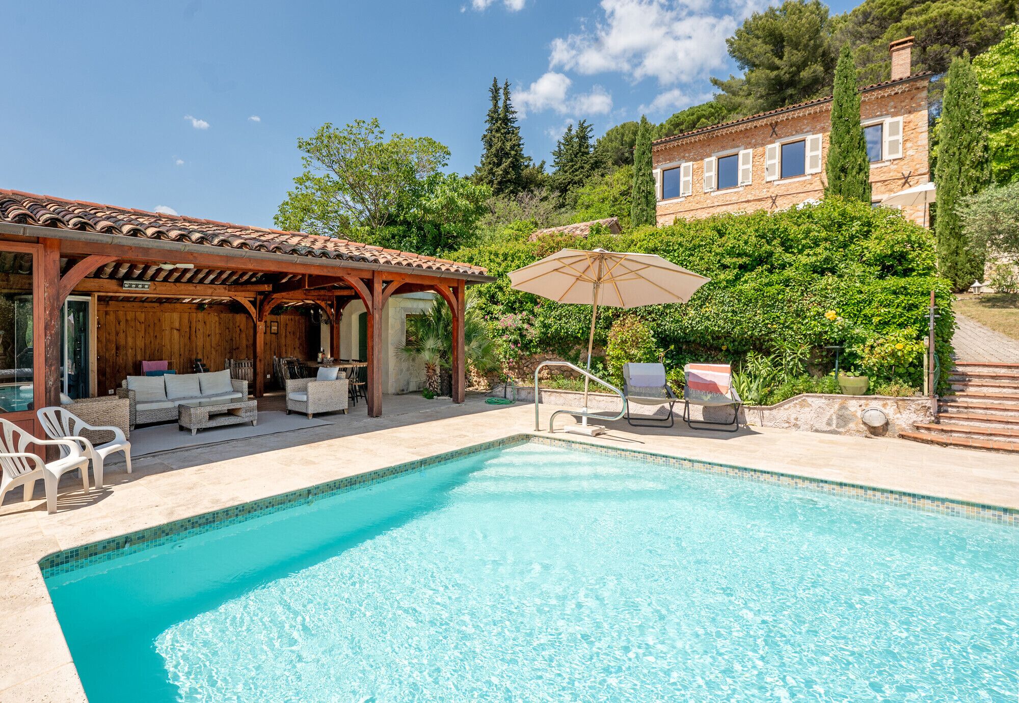 Une piscine avec des chaises longues et un espace de détente abrité.