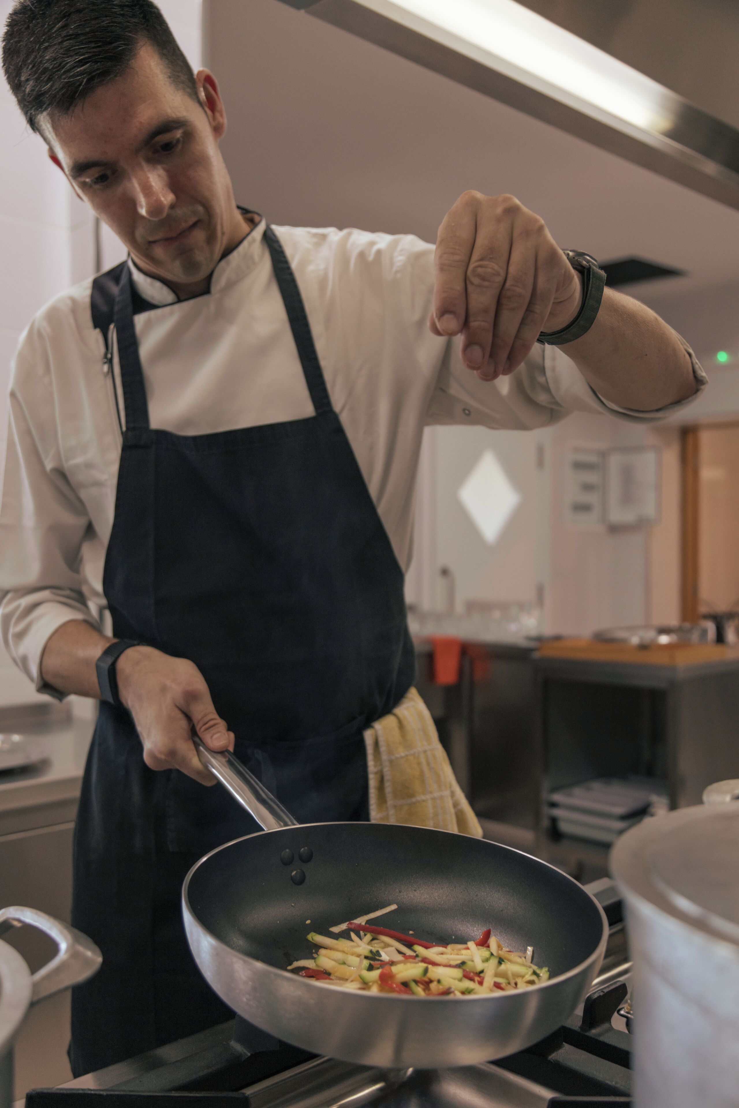 Une personne cuisine dans une cuisine, avec une poêle sur la cuisinière.