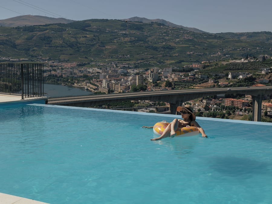 Una piscina con vistas a un paisaje urbano y montañas al fondo.