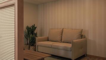 Un sofá de tonos neutros con cojines, una mesa de centro de madera y una planta en una cesta tejida.