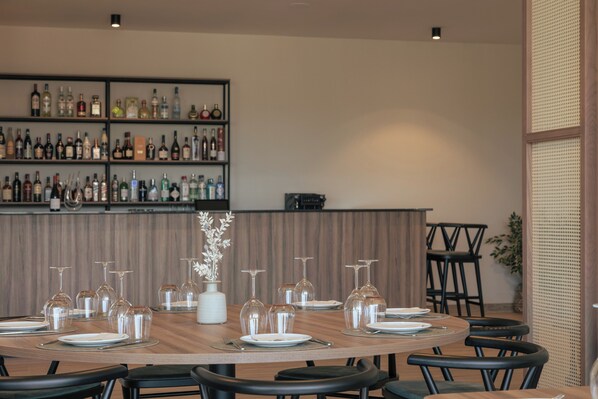 A restaurant interior with a long dining table set for a meal, surrounded by chairs.