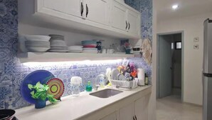A kitchen with white cabinets, a sink, and a countertop with dishes and utensils. - Beachfront Apartment | Ground Floor and Pool (Progreso)